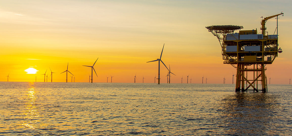 Photograph of an offshore wind farm and substation platform at sunset