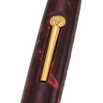 Close-up of the gold pocket clip and engraved finial on the burgundy marbled cap