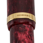 Close-up of the gold band hallmarked CS 375 on burgundy marbled acrylic