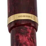Close-up of the gold band hallmarked CS 375 on burgundy marbled acrylic