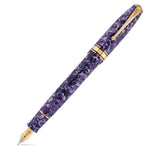 Series 100 Flecked Amethyst फाउंटेन पेन सफेद बैकग्राउंड पर, बैंगनी मार्बल्ड रेज़िन और गोल्ड ट्रिम