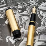 Conway Stewart Churchill Vermeil fountain pen and cap laid on a black-and-white photograph of Churchill in a crowd