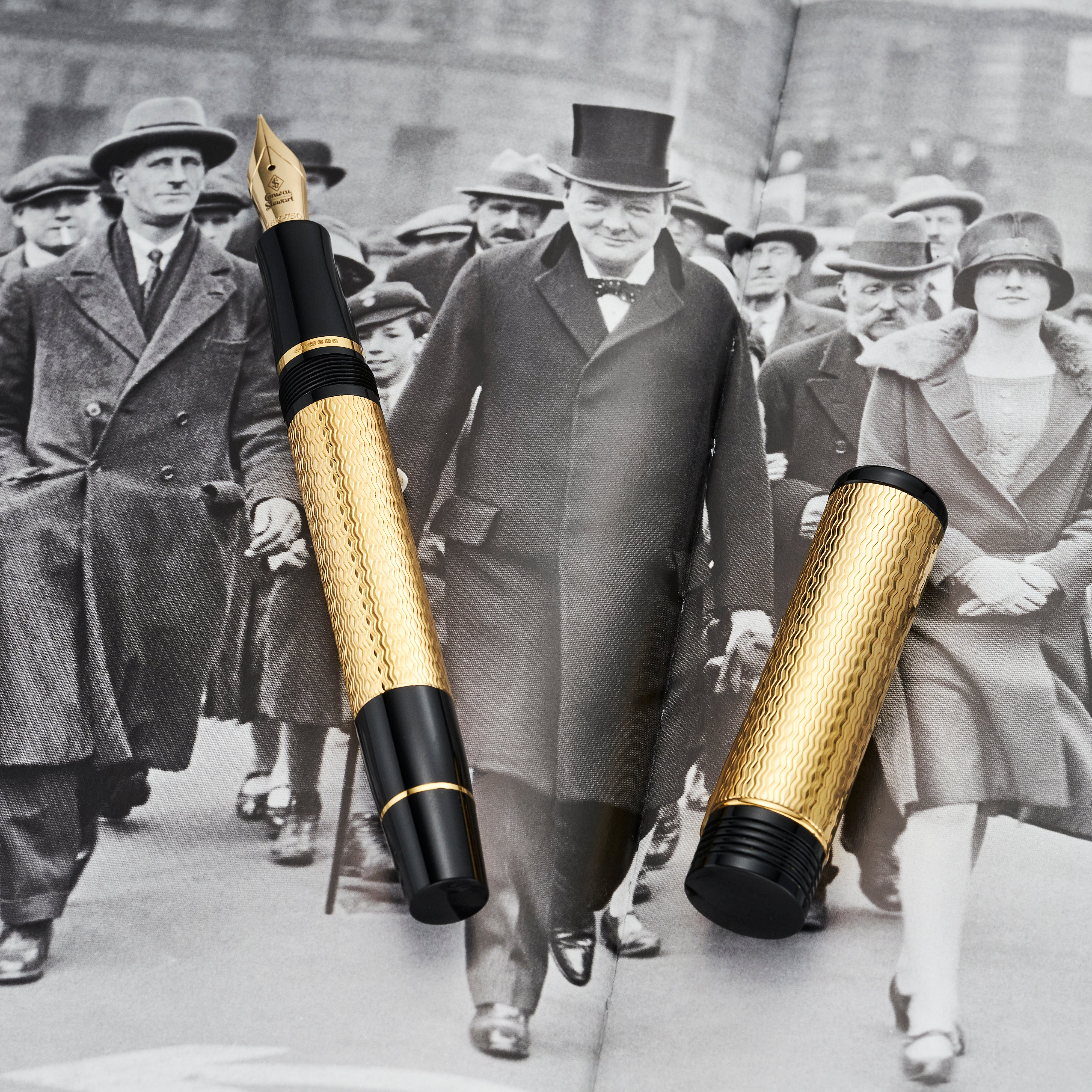 Conway Stewart Churchill Vermeil fountain pen and cap laid on a photograph of Churchill walking with a crowd