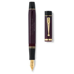Fountain pen uncapped in a flat lay, nib exposed, cap detached to the right showing the clip and crest