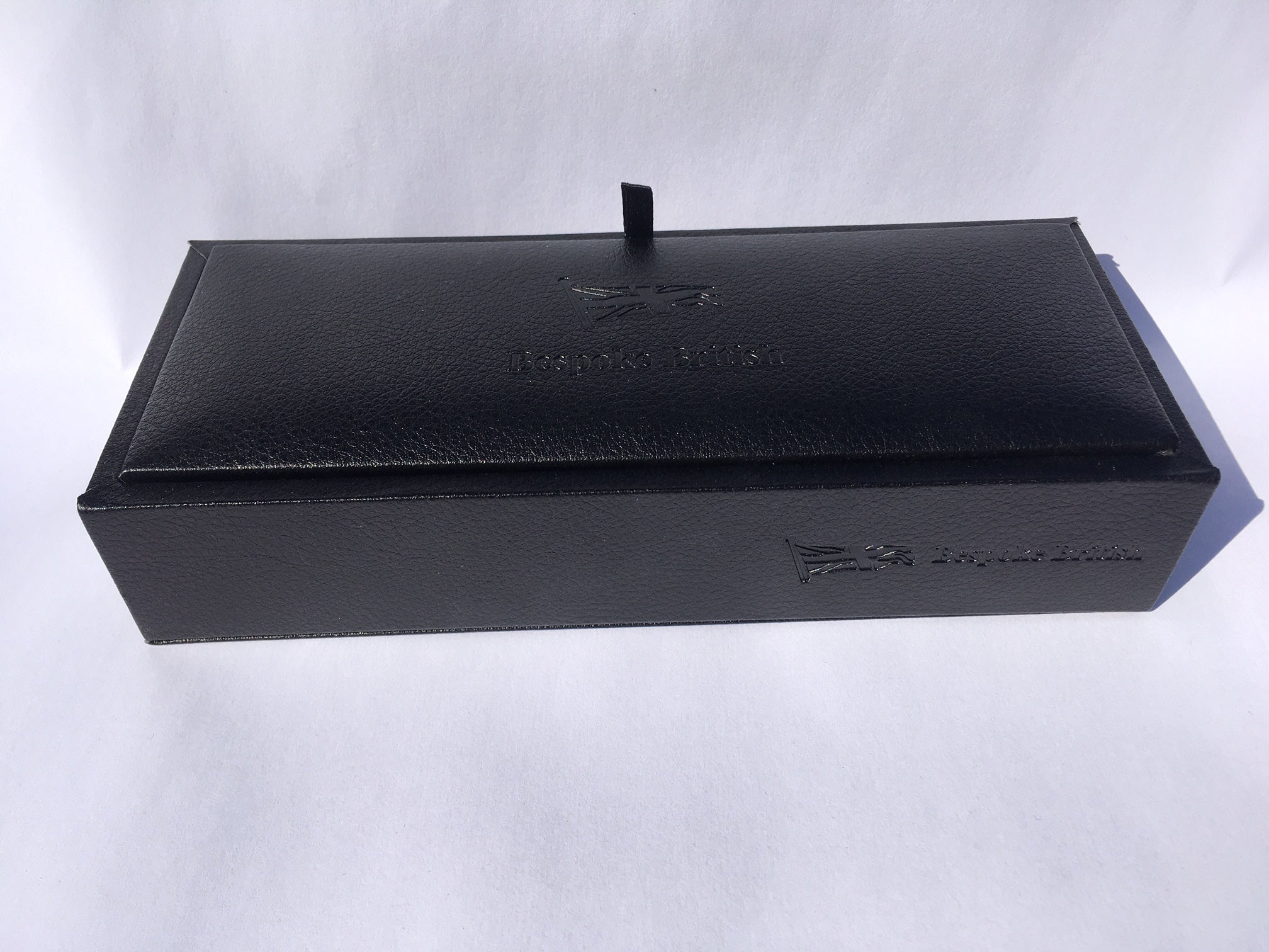 Estuche de presentación negro cerrado, repujado Bespoke British con una lengüeta para abrir