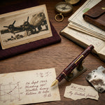 Burgundy marbled fountain pen displayed among WWII airman memorabilia and a handwritten flight log