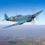 A Supermarine Spitfire aircraft banking in flight over the English countryside