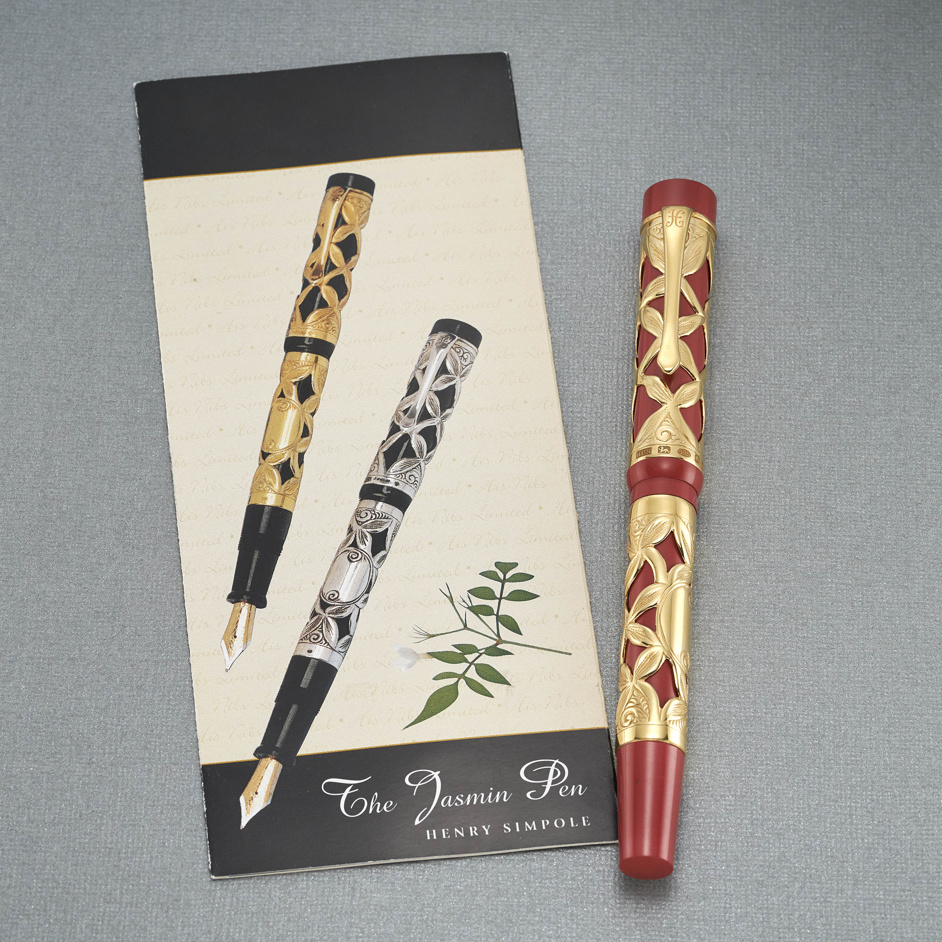 Jasmin Vermeil Stift mit geschlossener Kappe auf dem Umschlag des Jasmin-Pen-Hefts, mit Darstellung der Gold- und Silberversionen