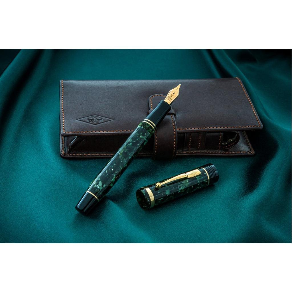 Churchill Bracket Green pen resting capped on its brown leather pouch on dark green fabric