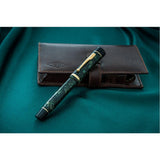 Churchill Bracket Green pen lying across its brown leather pouch, viewed from a different angle