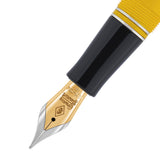 Makroaufnahme der goldenen Feder und des schwarzen Griffstücks des Churchill Cloisonne Yellow Füllfederhalters