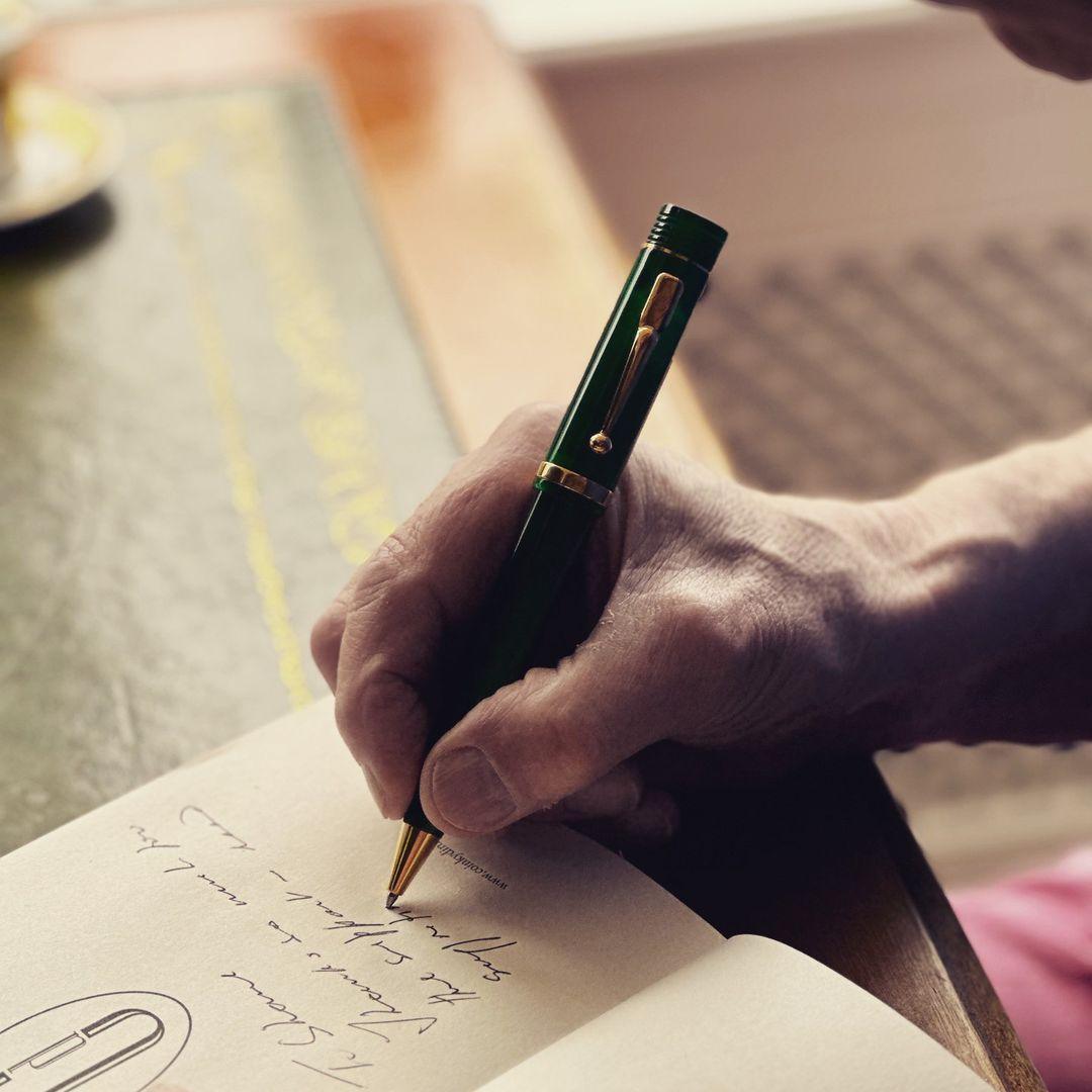 Handschrift in einem Notizbuch mit dem Churchill Evergreen Kugelschreiber an einem Holzschreibtisch