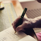 Handschrift in einem Notizbuch mit dem Churchill Evergreen Kugelschreiber an einem Holzschreibtisch