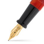 Nahaufnahme der Collectors Pen Black Whirl Feder in Goldton vor rot-orange marmoriertem Acryl-Griffstück