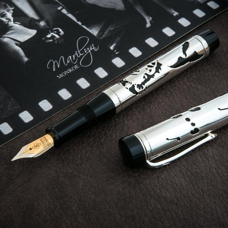 Marilyn Monroe Overlay geöffnet mit goldener Feder, Kappe abgenommen, neben Präsentationskarte im Filmstreifen-Design