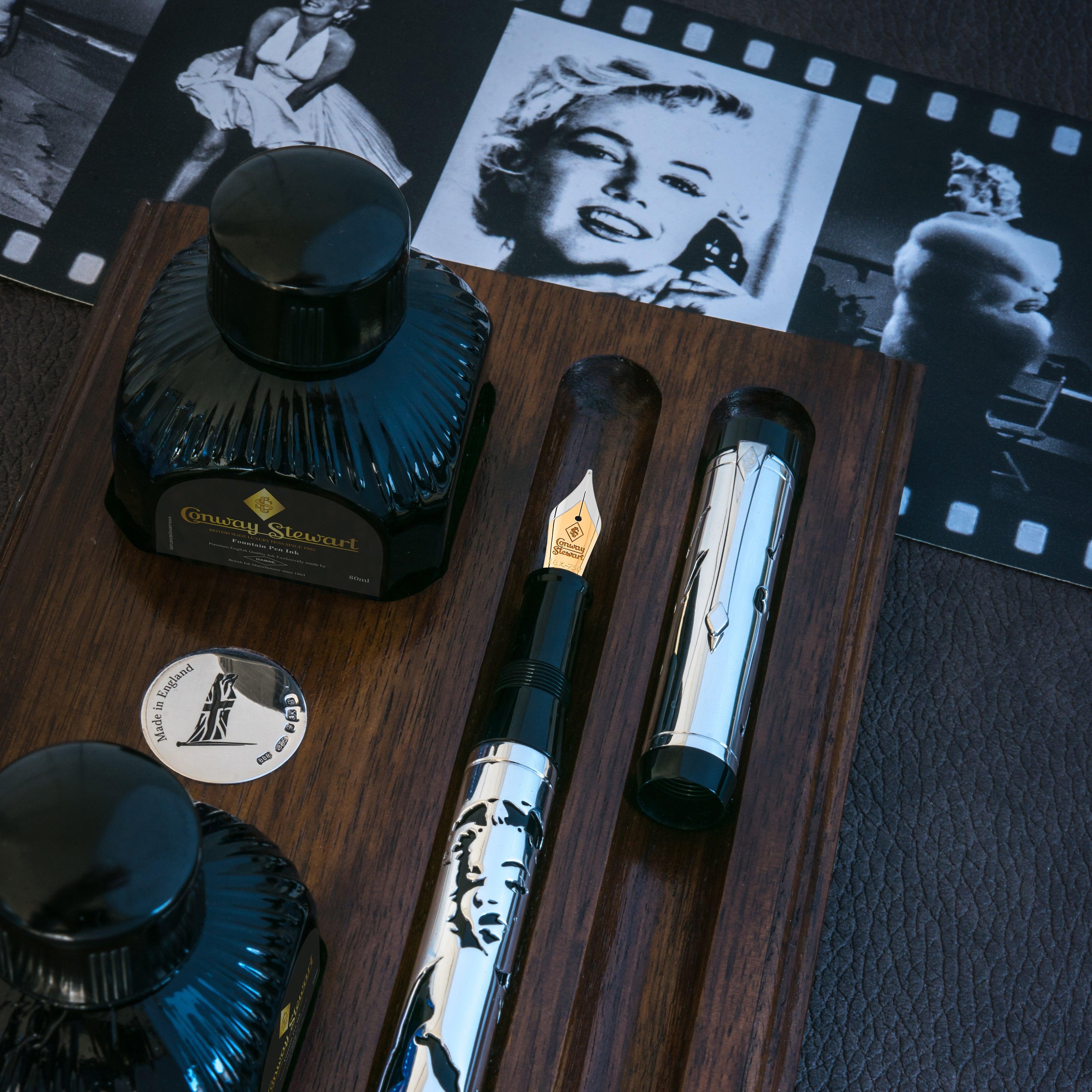 Cuerpo y capuchón Marilyn Monroe Overlay en bandeja de madera junto a frascos de tinta Conway Stewart y fotografías