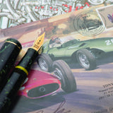 Vanwall pen cap and nib resting on an illustrated page of racing cars and commemorative stamps
