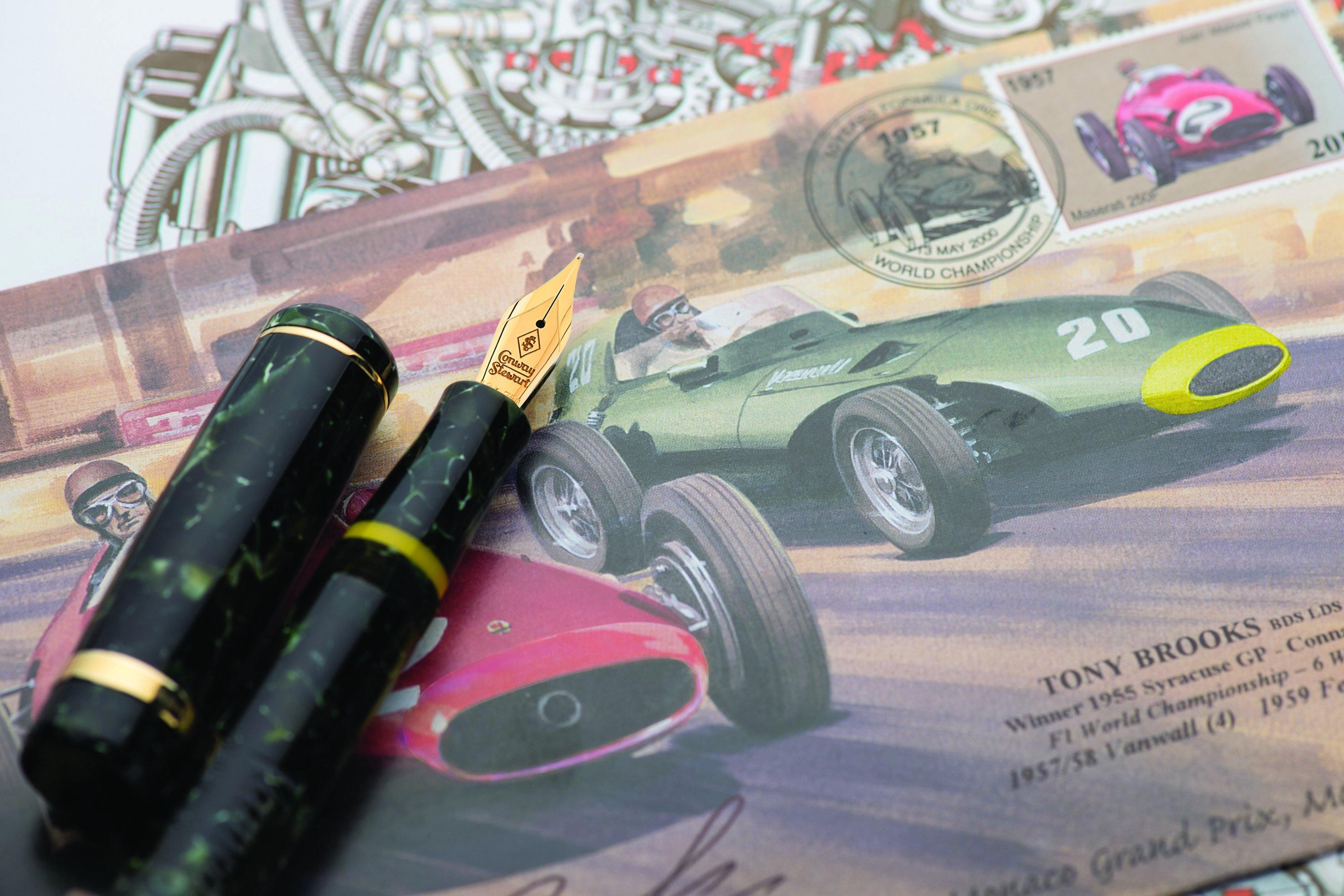 Vanwall pen cap and nib resting on an illustrated page of racing cars and commemorative stamps