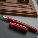 Winston Cherry Red Füllfederhalter mit Kappe über Kreuz auf einem Notizbuch, unter Stiftablage und Tintenflaschen
