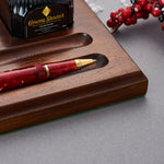 Winston Cherry Red Tintenroller liegt in einer Nussbaum-Schreibtischablage neben einer Flasche Conway Stewart Tinte
