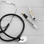 Doctor's Pen Füllfederhalter und Kappe liegen neben einem Stethoskop auf einer Holzoberfläche