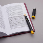 Alan Turing Pen resting on an open book page reproducing Turing's handwritten notes, cap standing beside it
