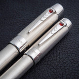 Par de Wedding Pens en plata de ley guilloché, con clips de cabujón de rubí, apoyadas juntas sobre una superficie de piel negra
